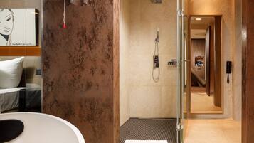 A modern bathroom with a glass shower enclosure, a visible toilet, and a towel on the floor.