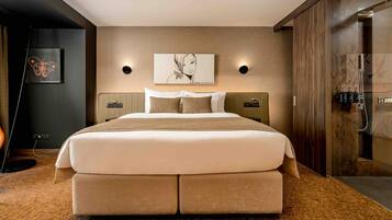 Ein modernes Hotelzimmer mit einem großen Bett, einem Holzkopfstück, einem an der Wand befestigten Kunstwerk und einer integrierten Dusche.