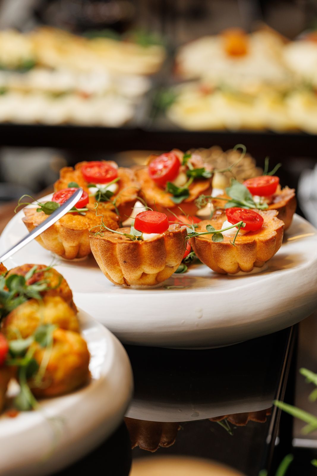 A plate of mini quiches garnished with tomatoes and greens.