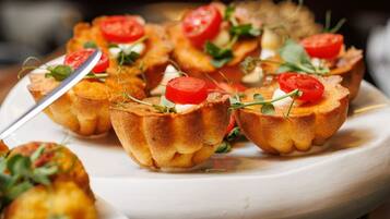A plate of mini quiches garnished with tomatoes and greens.