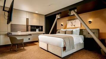 Una habitación de hotel moderna con cama, escritorio, silla, televisor y una obra de arte colgada en la pared.