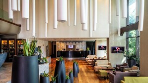 A spacious lobby with a reception desk, seating area, and large potted plants. - Kronwell Brasov Hotel (Brasov)