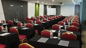 A conference room with rows of tables and chairs, equipped with water bottles and nameplates.