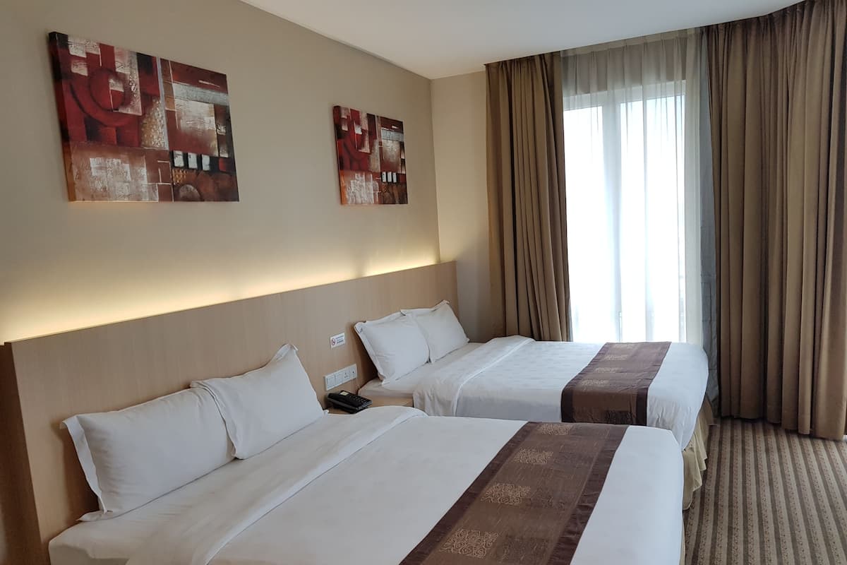 Hotellihuone, jossa on kaksi sänkyä, beigenväriset seinät ja kaksi abstraktia maalausta.