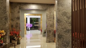 A hallway with a marble wall, a glass door leading to a room, and a potted plant with flowers. - DeHome Boutique Hotel (Kuching)