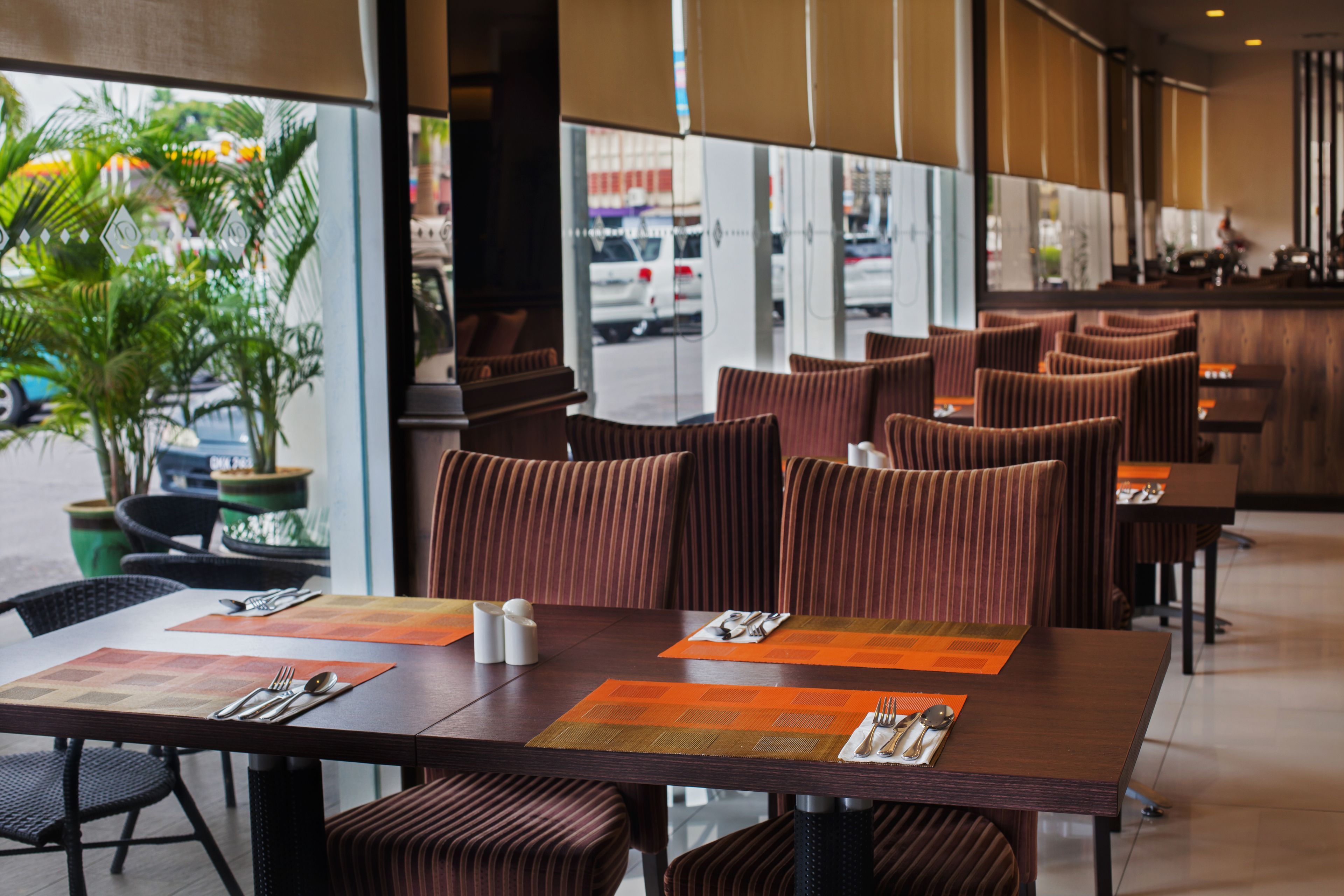 A restaurant with a modern interior, featuring striped cushioned booths and a large window overlooking the street.