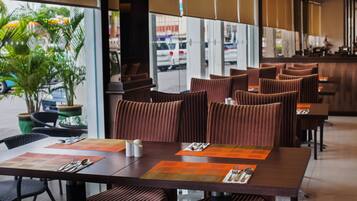 A restaurant with a modern interior, featuring striped cushioned booths and a large window overlooking the street.