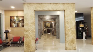A hotel lobby with a modern design, featuring a reception desk, seating area, and a decorative wall. - DeHome Boutique Hotel (Kuching)