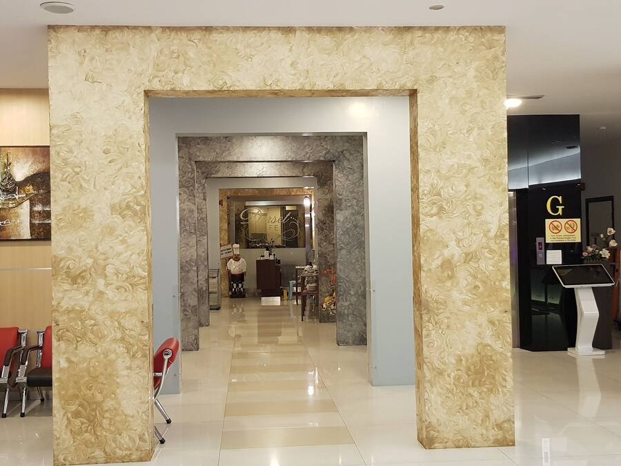 Um hall de hotel com design moderno, com uma mesa de recepção, área de estar e um painel decorativo.