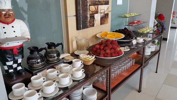 A buffet setup with various food items, coffee and tea stations, and a decorative chef figure. - DeHome Boutique Hotel (Kuching)