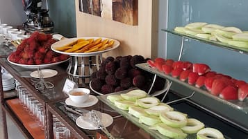 A buffet with various fruits and a chef statue.