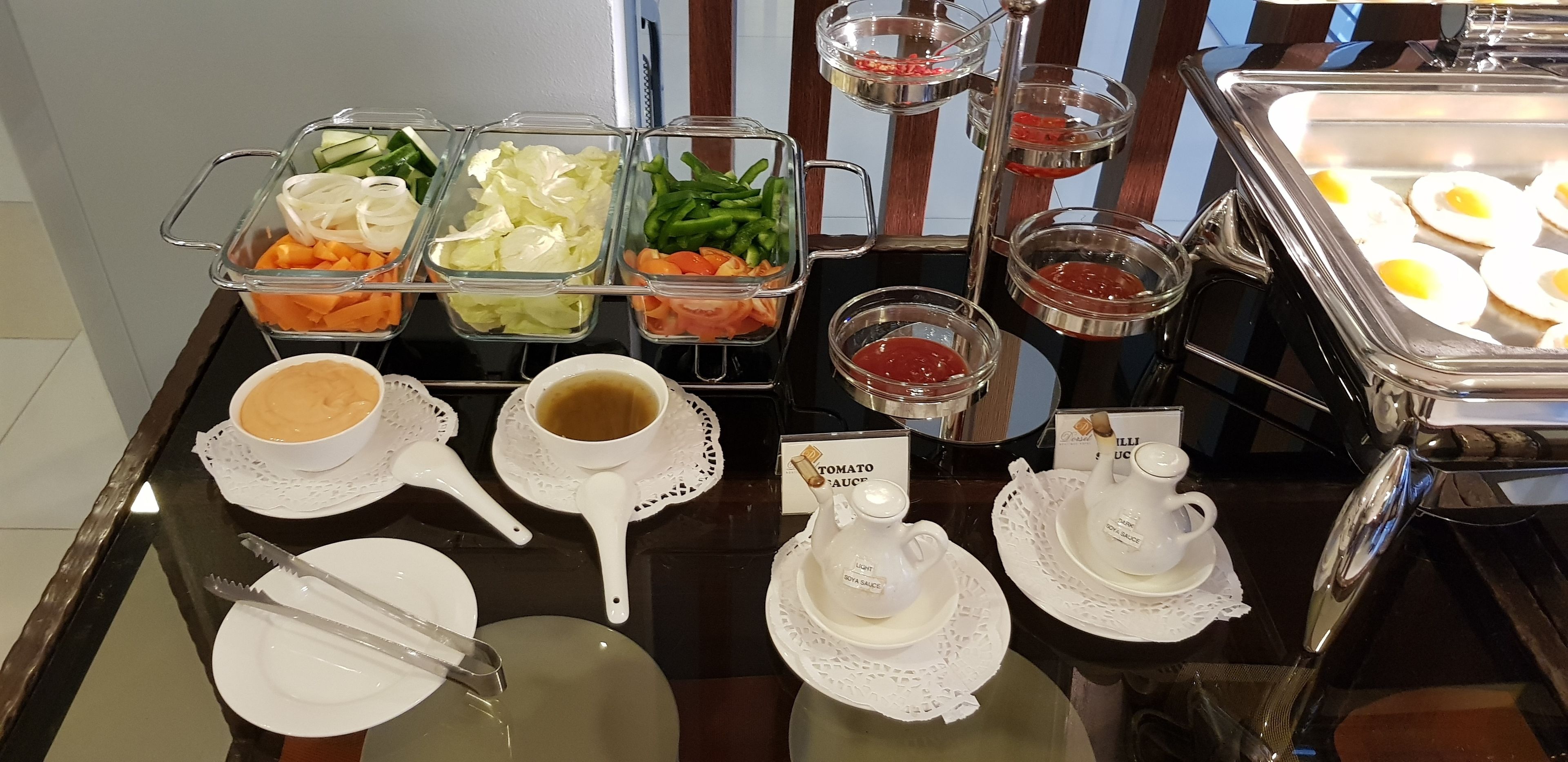 Een buffet met diverse gerechten en bijbehorende sauzen.
