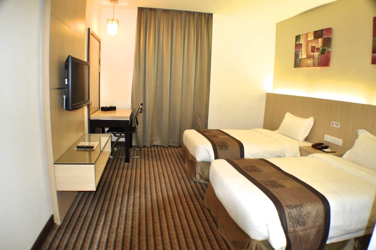 Hotellihuone, jossa on kaksi sänkyä, työpöytä, televisio ja verho.