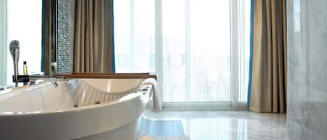 A spacious bathroom with a large bathtub, a mirror, and a vanity with toiletries.