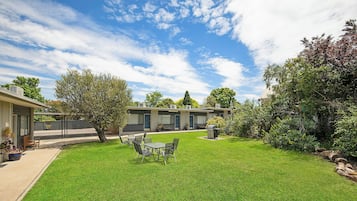 A well-maintained outdoor area with a lawn, seating, and a barbecue grill.
