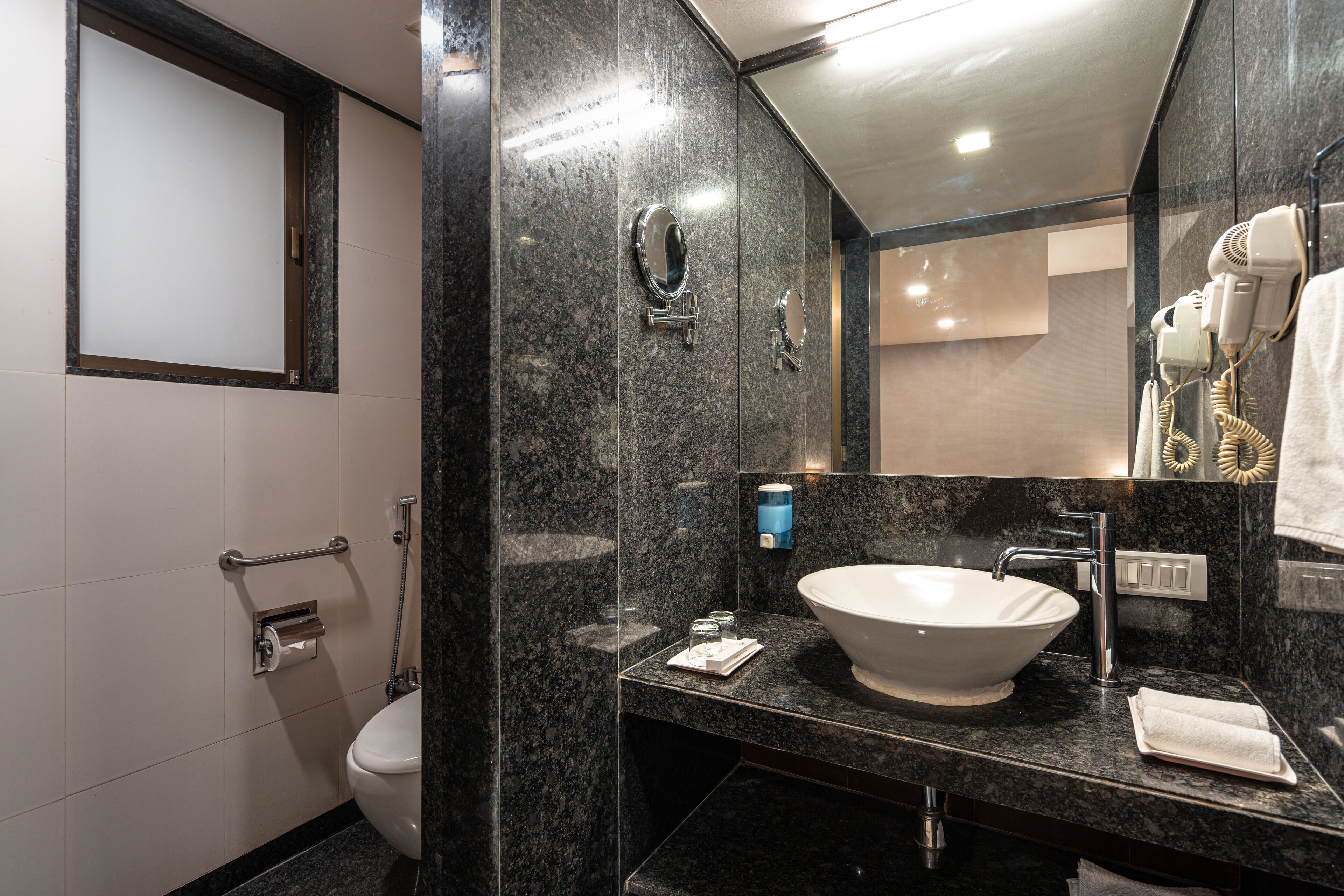 A modern bathroom with a large mirror, a sink, and a toilet.