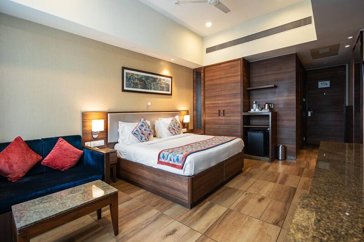 A hotel room with a bed, a desk, a chair, a small kitchenette, and a wardrobe.