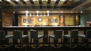 A bar area with a wooden counter, bar stools, and a clock. - GCC Hotel and Club (Mumbai)
