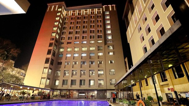 A hotel with a large outdoor pool, multiple floors, and a modern architectural design. - GCC Hotel and Club (Mumbai)