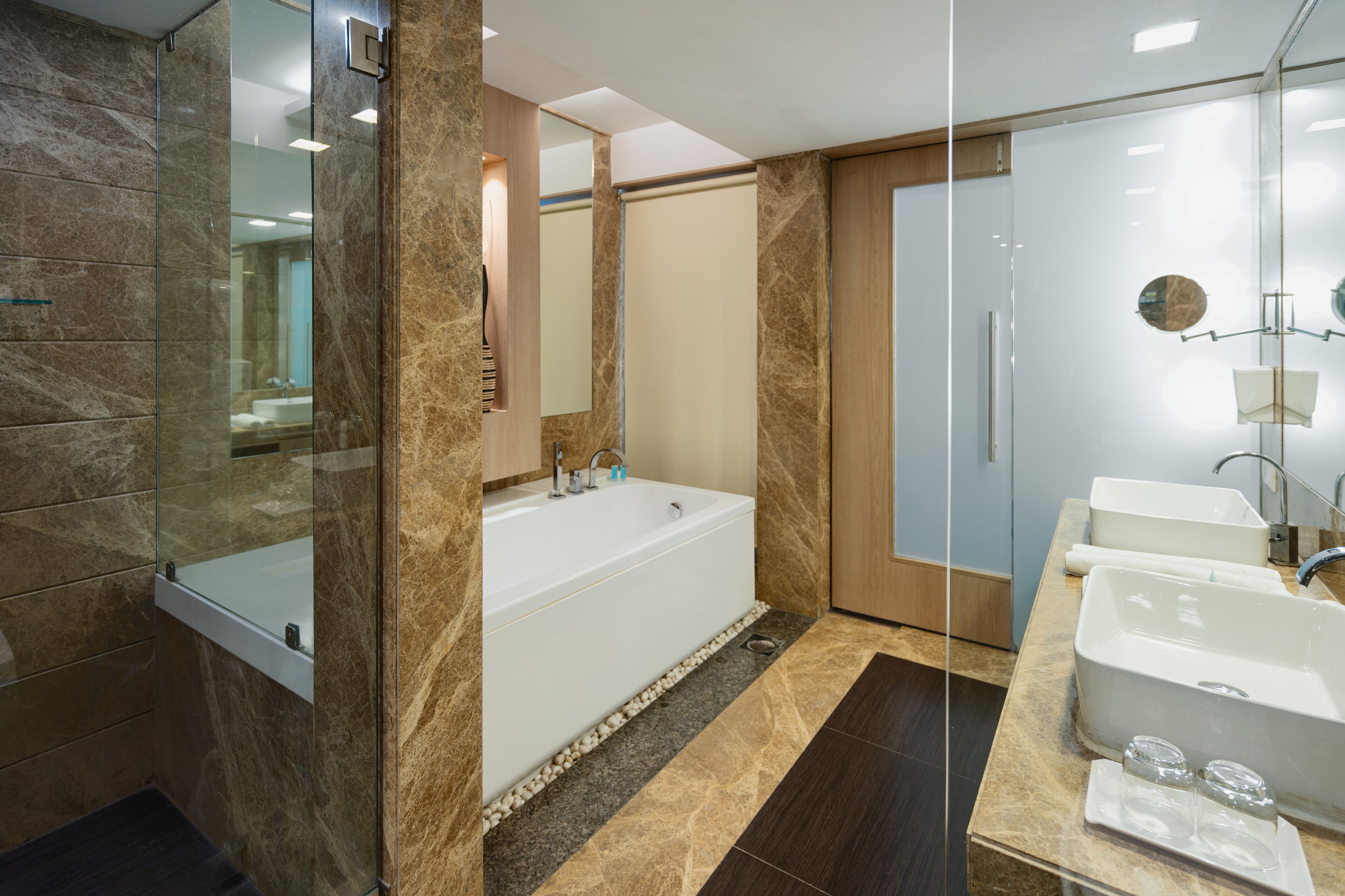 Un baño moderno con ducha de vidrio, una bañera independiente y un lavamanos doble.