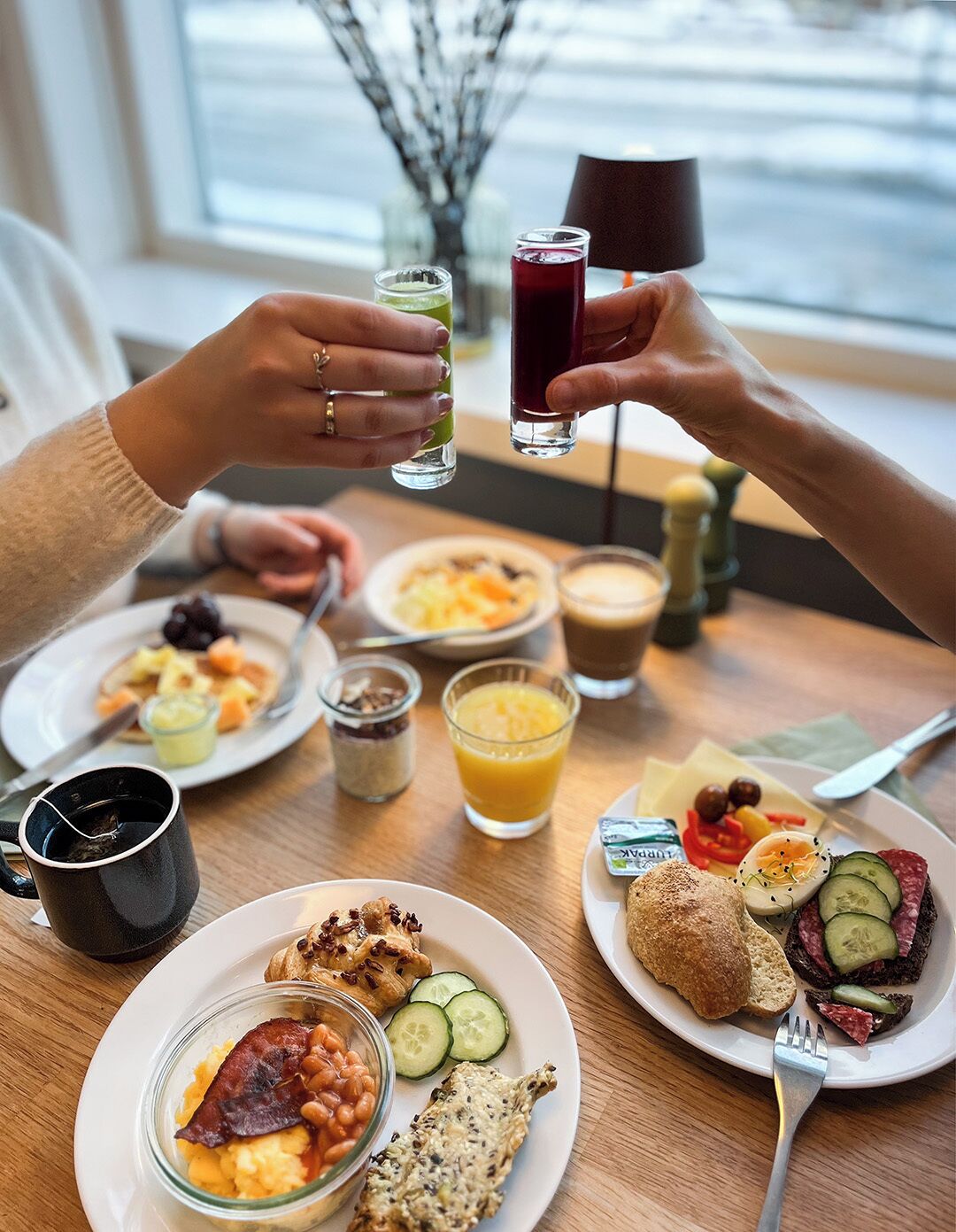 A breakfast setting with various dishes, drinks, and a coffee cup on a table.