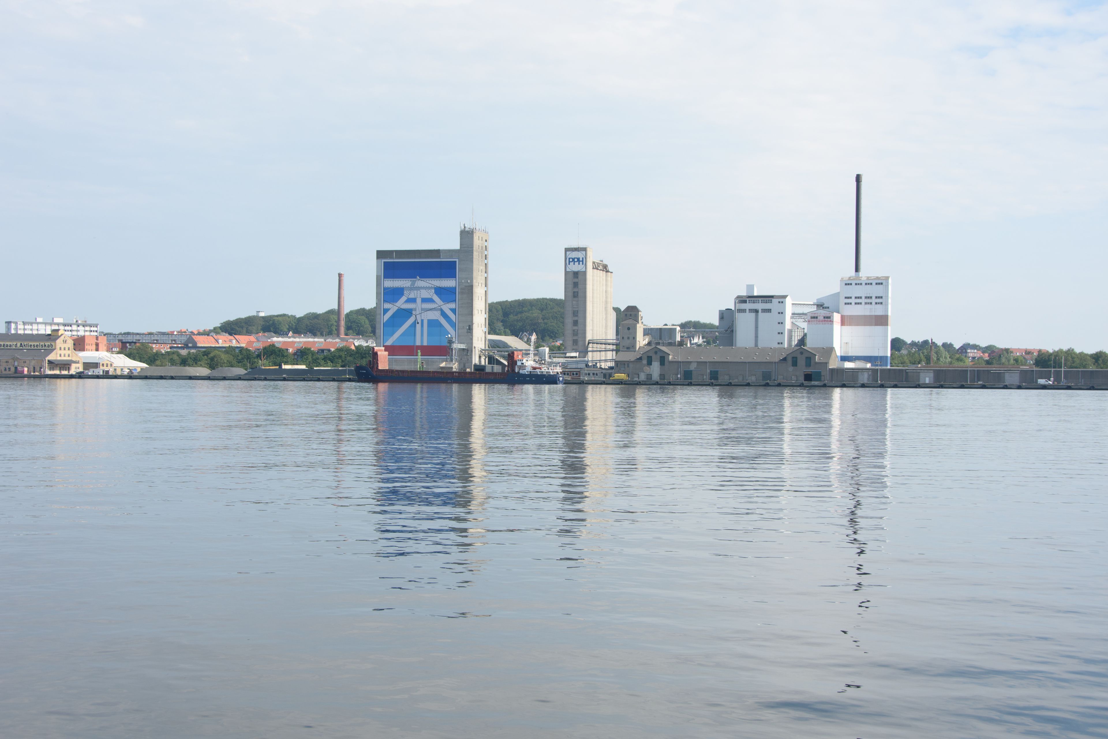 Une zone industrielle située au bord de l’eau, avec des bâtiments et une grande enseigne bleue.