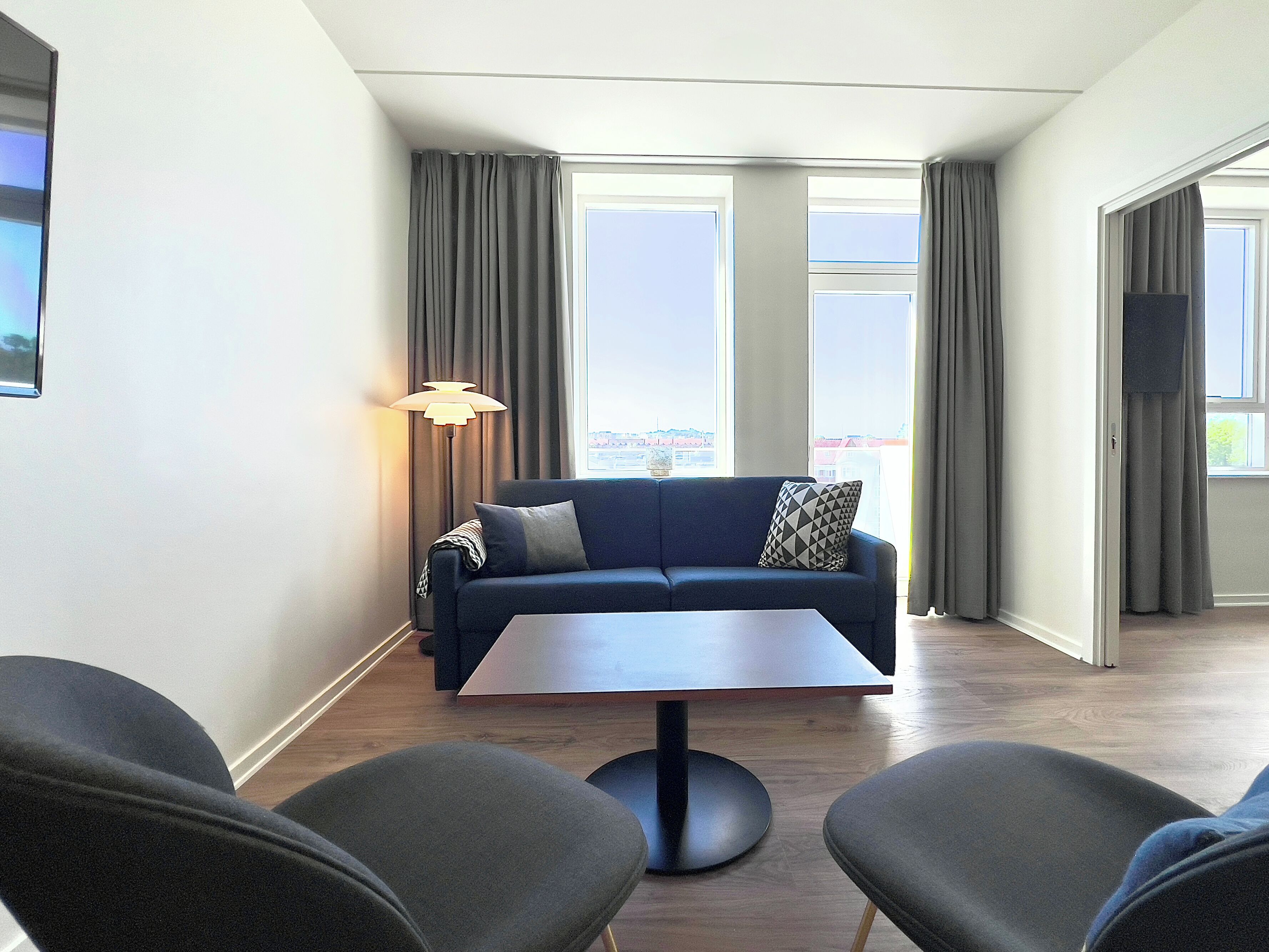 A modern living room with a sofa, two armchairs, a coffee table, and a floor lamp.