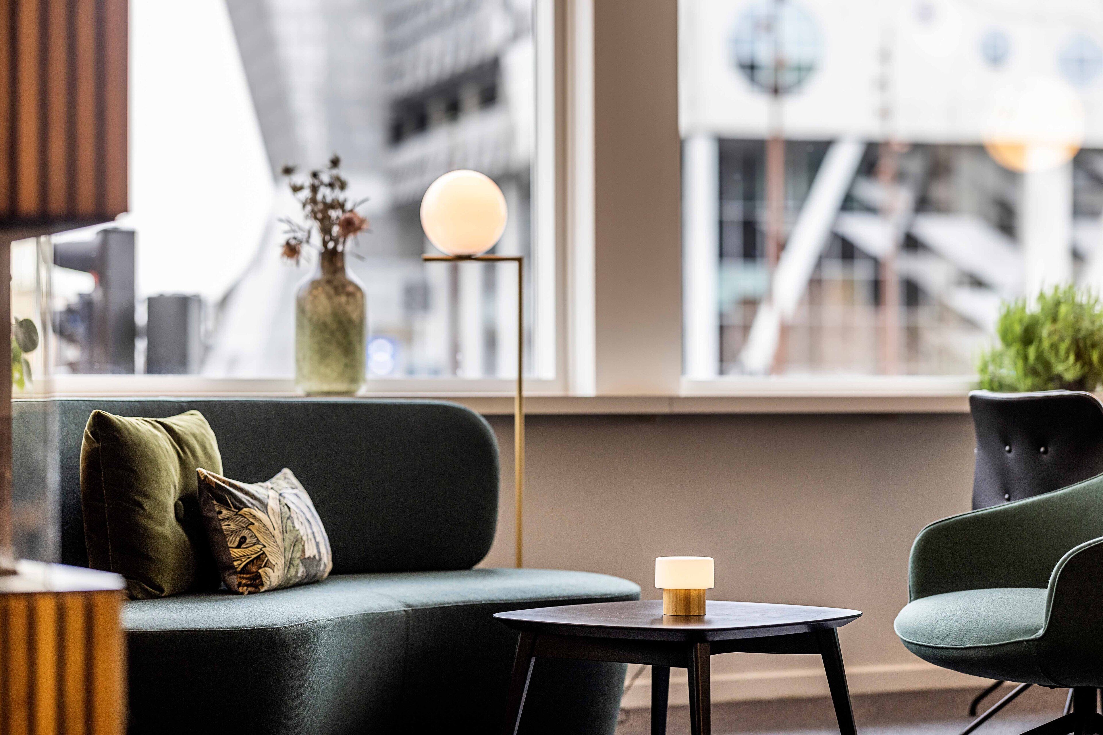 A modern interior with a dark green sofa, a small round table, and a floor lamp with a spherical light.