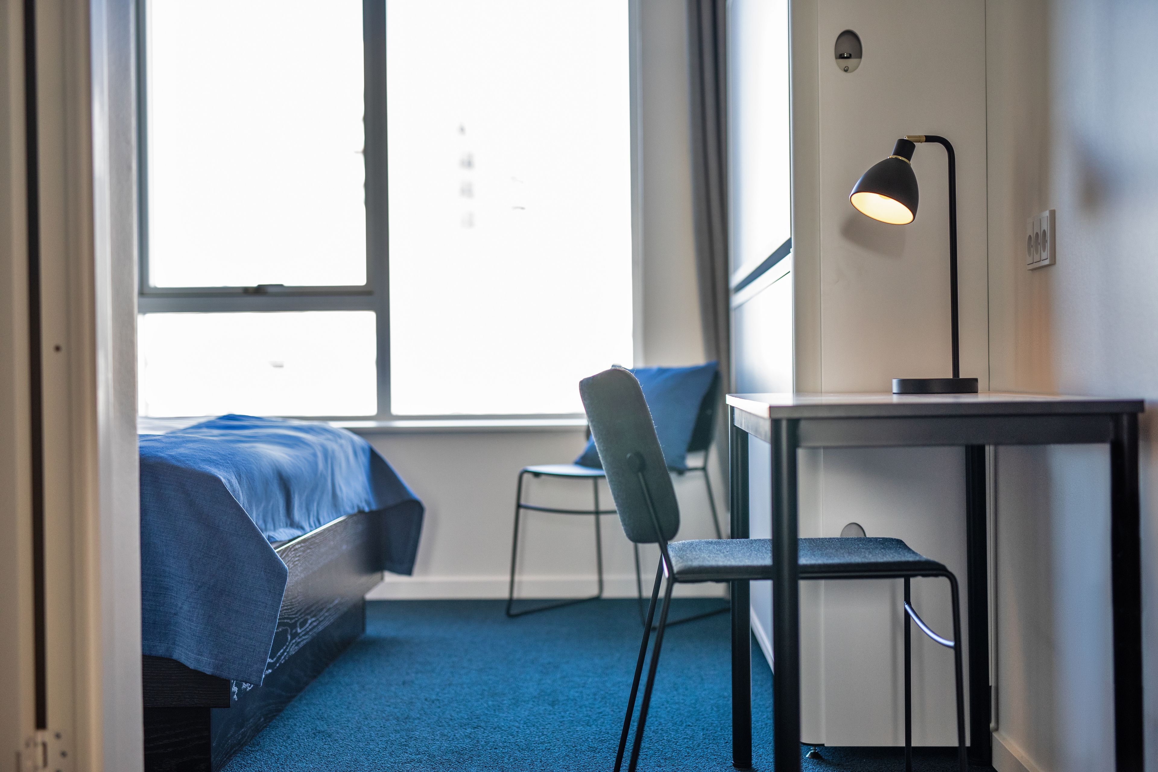 Una habitación de hotel con una cama, un escritorio, una silla y una ventana.