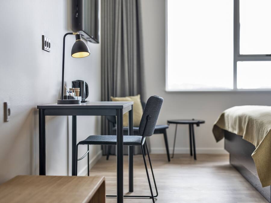 Una habitación de hotel moderna con escritorio, silla y cama.