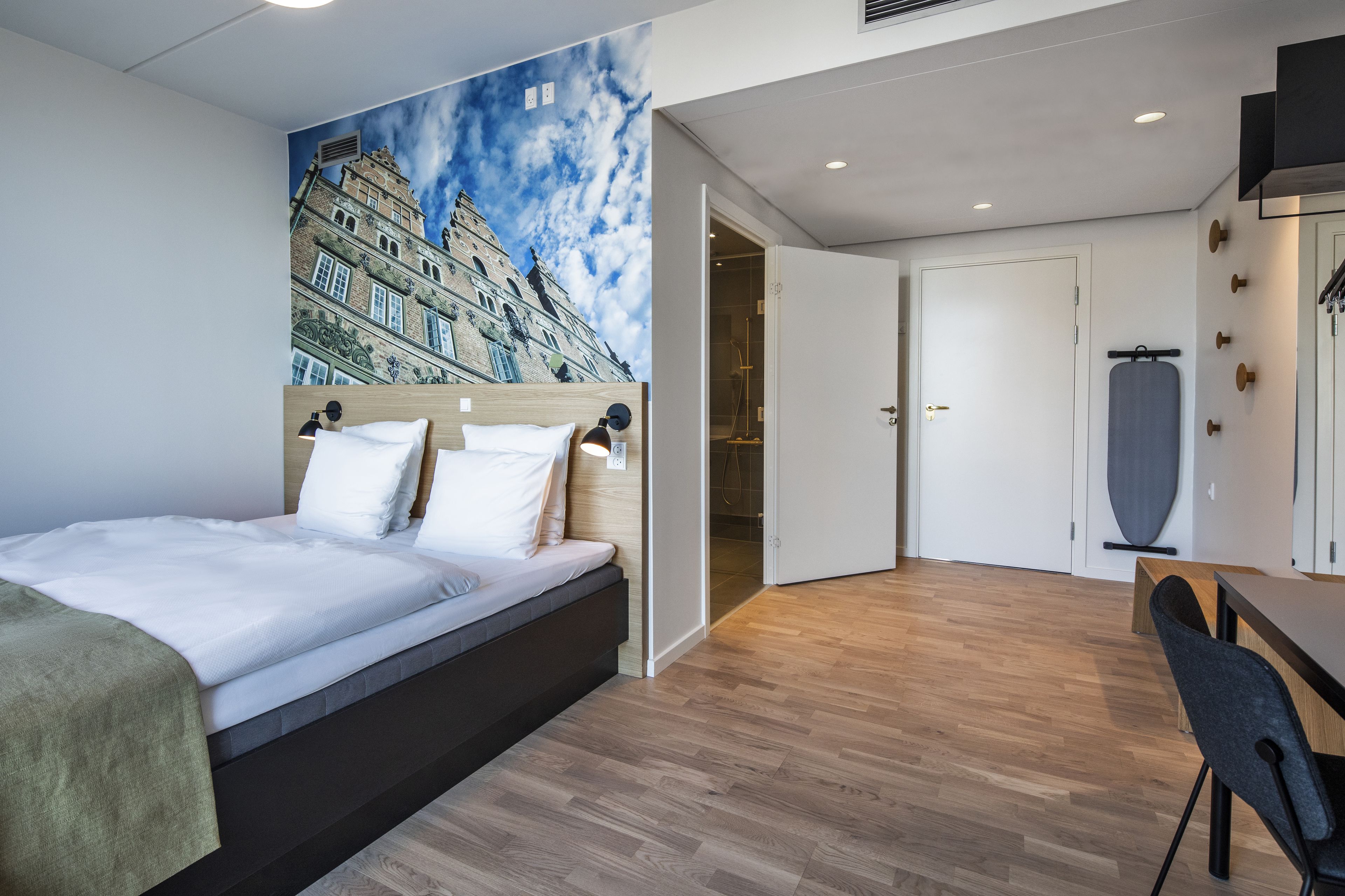 Una habitación de hotel moderna con cama, zona de comedor y ducha.