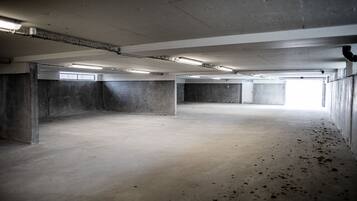 An empty parking garage with concrete walls, a flat floor, and fluorescent lighting.
