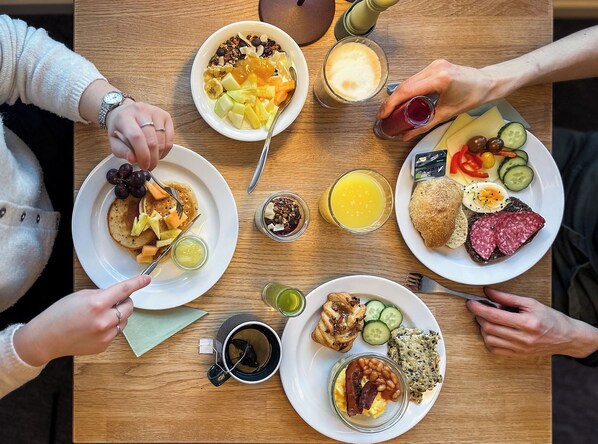 Uma mesa de café da manhã com diversos pratos, incluindo panquecas, torradas, ovos e frutas.