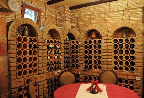 A wine cellar with brick walls and multiple wine racks. - Millenium Palace Bitola (Bitola)