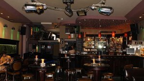 A bar area with multiple stools, a bar counter, and a bartender. - Millenium Palace Bitola (Bitola)