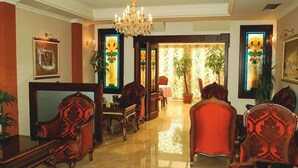 A spacious lobby with a chandelier, comfortable seating, and large windows with decorative glass panels. - Millenium Palace Bitola (Bitola)