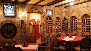 A rustic restaurant interior with stone walls, a large wine rack, and a traditional fireplace. - Millenium Palace Bitola (Bitola)