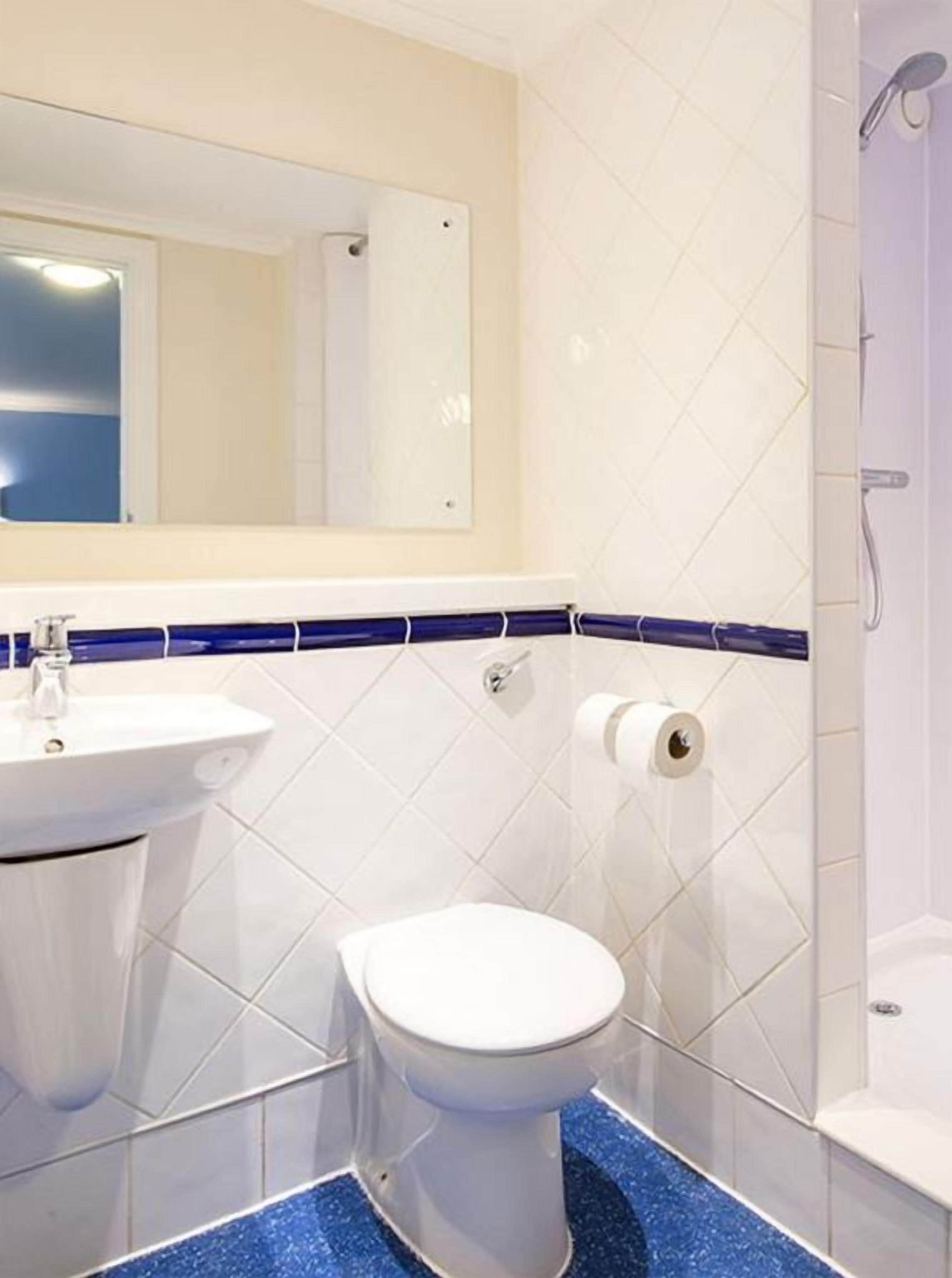 A bathroom with a white sink, toilet, and shower.