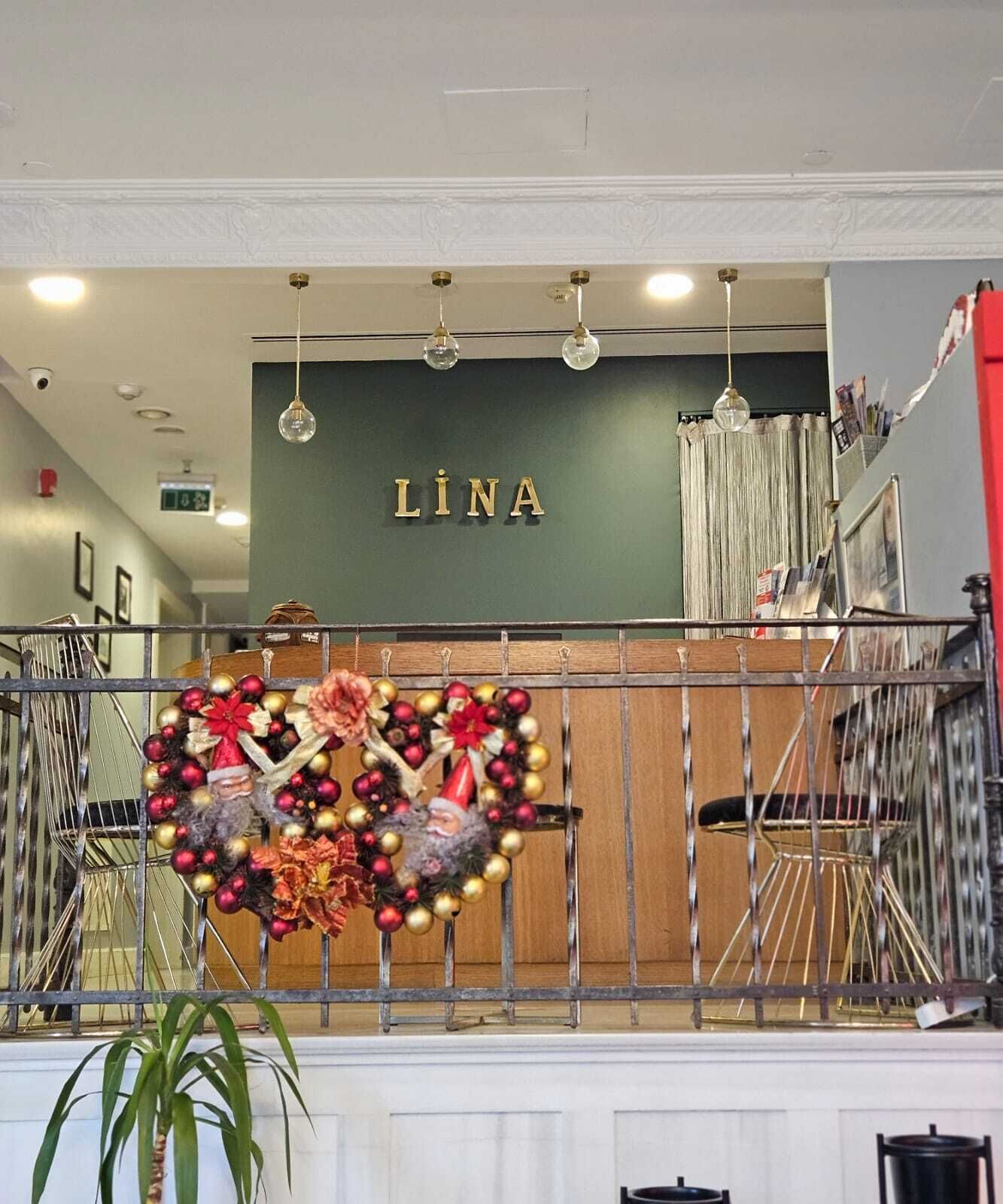 Un área de recepción con una pared verde y una placa que dice 'LINA'.