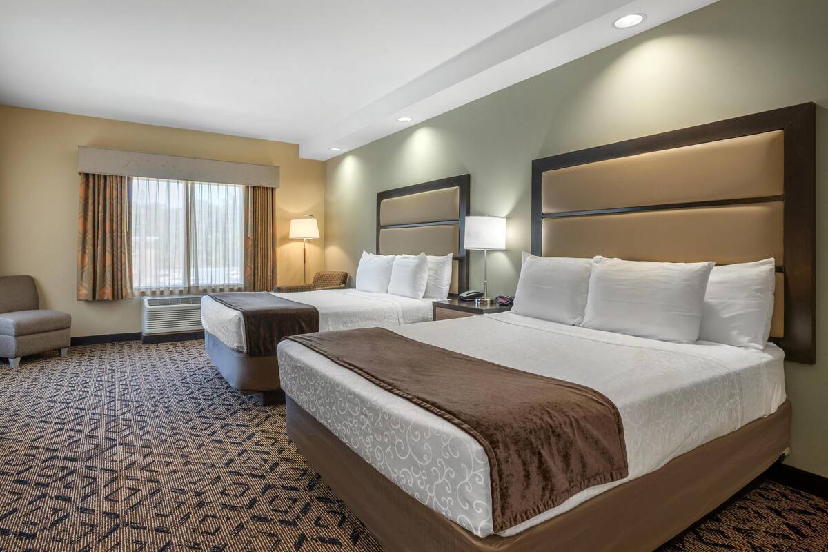Een hotelkamer met twee bedden, een bank, een bureau en een lamp.