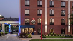Un hotel de varios pisos con fachada de ladrillo, un letrero Best Western PLUS y una entrada bien iluminada.