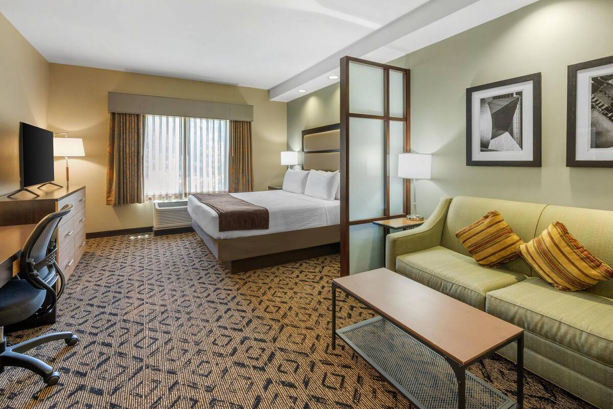 Een hotelkamer met een bed, een slaapbank, een bureau en een televisie.