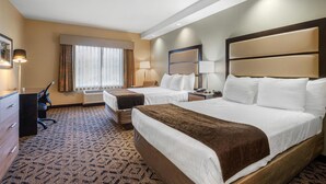 Habitación de hotel con dos camas, un escritorio y una silla.