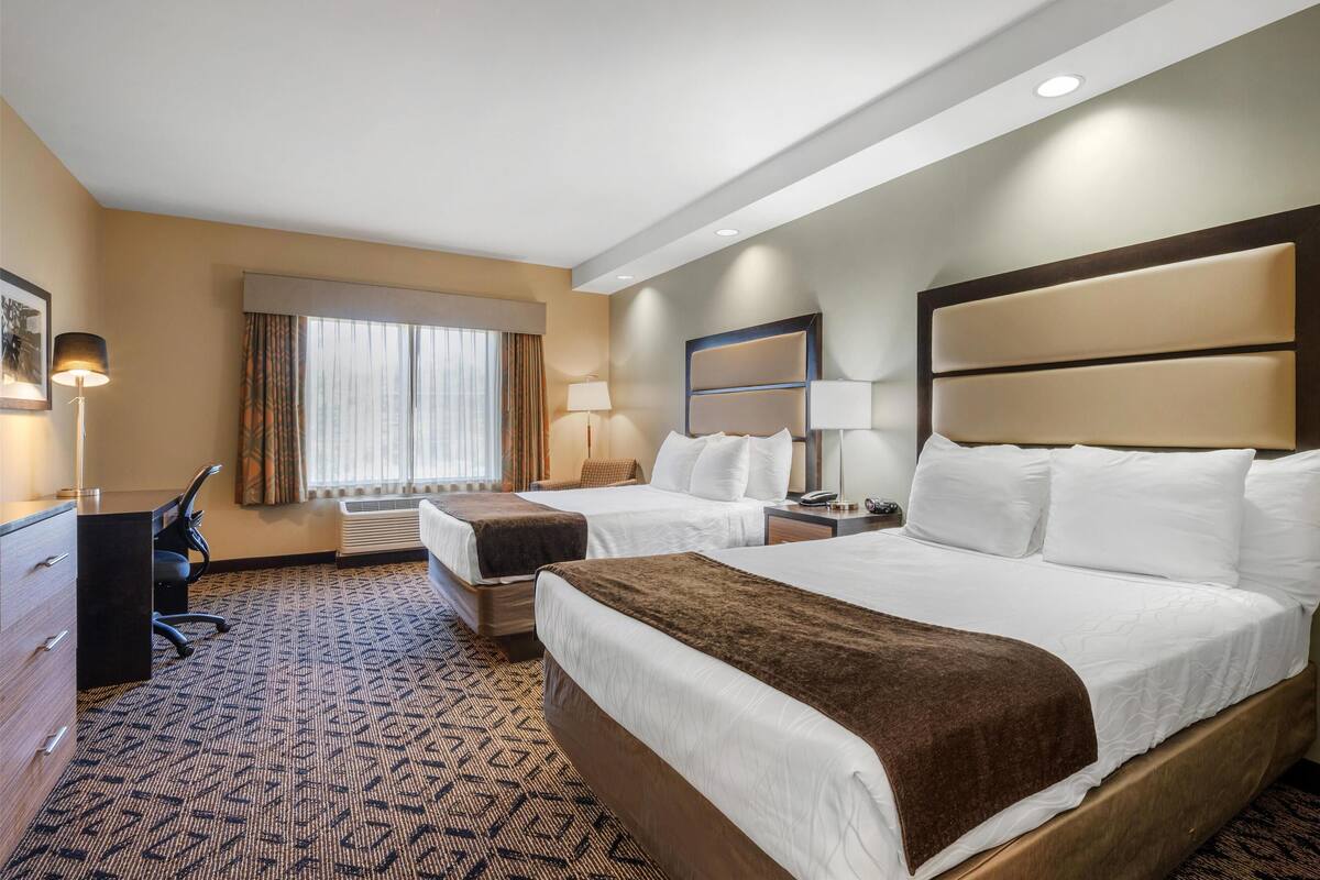 Een hotelkamer met twee bedden, een bureau en een stoel.