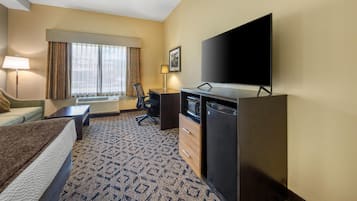 A hotel room with a bed, desk, chair, television, and a large window with curtains.