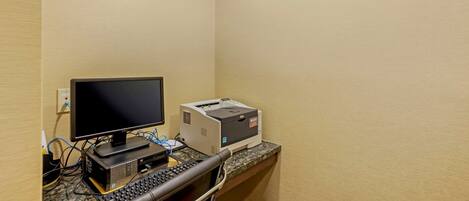 A small workspace with a desktop computer, monitor, keyboard, and printer on a granite countertop.