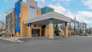 A Comfort Inn hotel with a modern facade, a covered entrance, and an American flag.