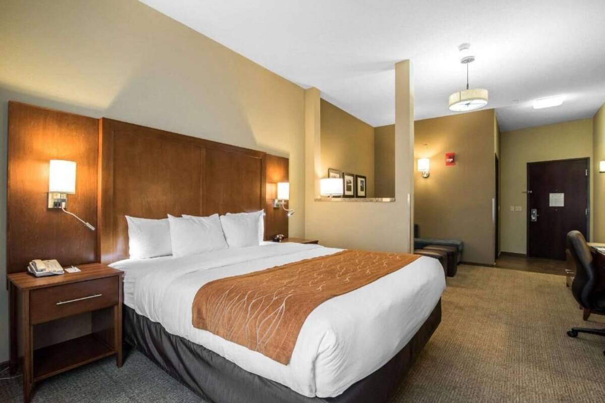 A hotel room with a large bed, bedside lamps, a desk, and a chair.