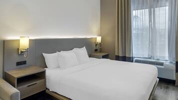 A hotel room with a large bed, bedside tables, a lamp, and a window with curtains.