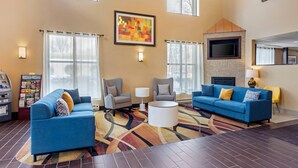 A hotel lobby with a blue sofa, armchairs, a coffee table, and a fireplace.
